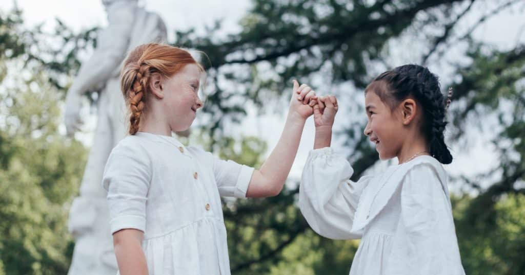 Two little girls making a pinky promise https://www.autismparentingmagazine.com/relationship-skills-autistic-children-young-adults/