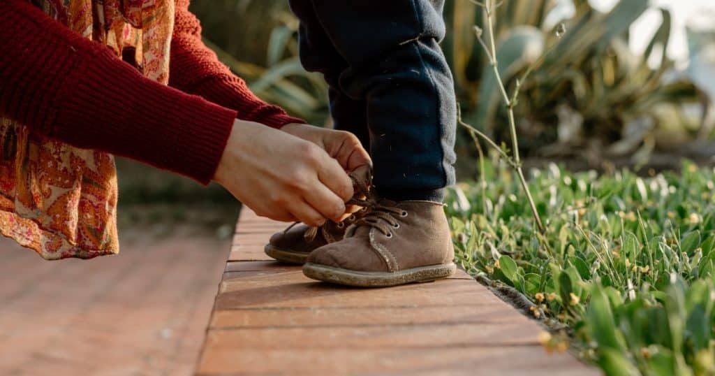 Mom tying her child's shoes https://www.autismparentingmagazine.com/autism-and-clumsiness/