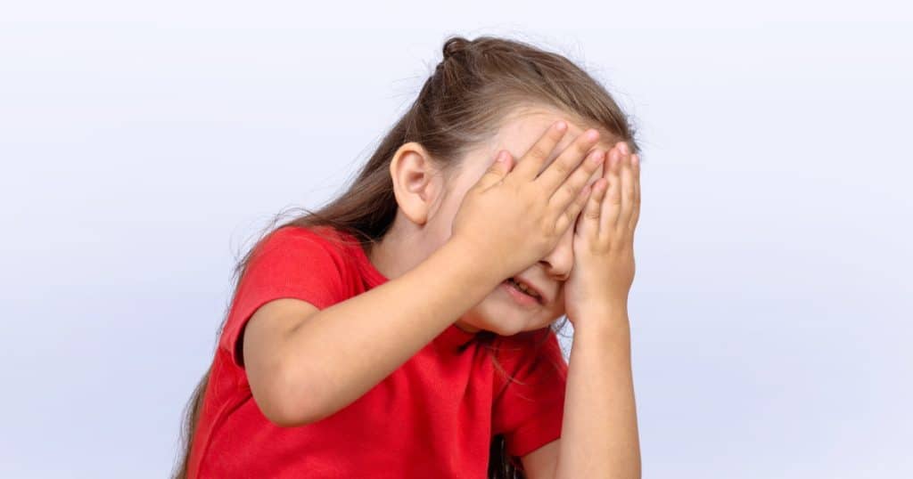 Little girl covering her face with her hands https://www.autismparentingmagazine.com/bossy-behavior-in-autism/