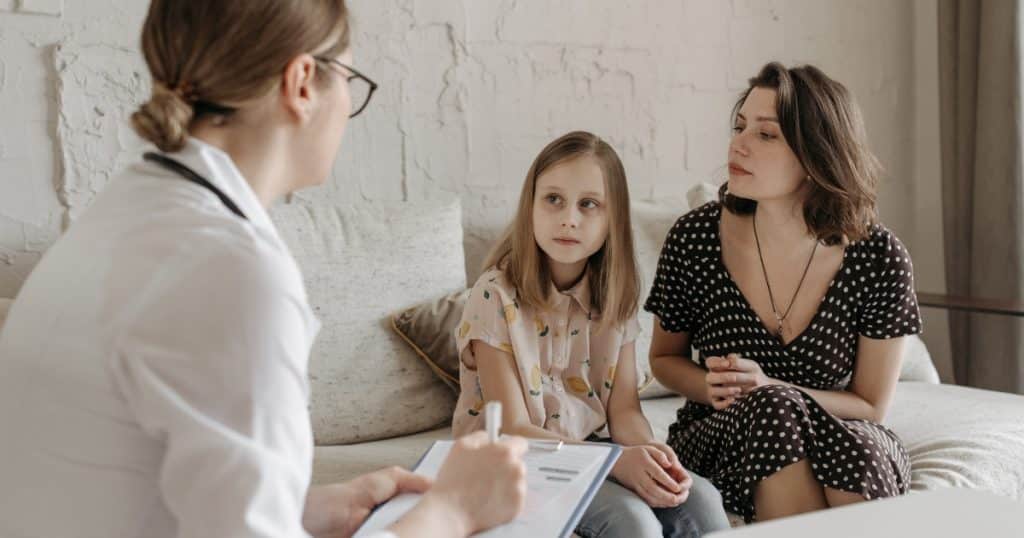 Managing seizures in autistic children Woman and her daughter talking to a doctor https://www.autismparentingmagazine.com/autism-and-seizures/