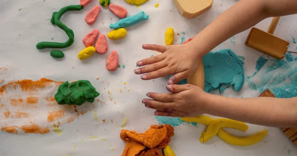 A child playing with playdough https://www.autismparentingmagazine.com/fall-sensory-activities/