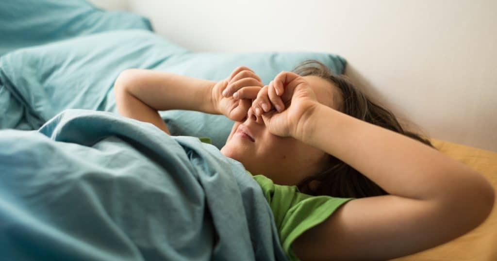 Child rubbing eyes in bed https://www.autismparentingmagazine.com/night-terrors-and-autism/