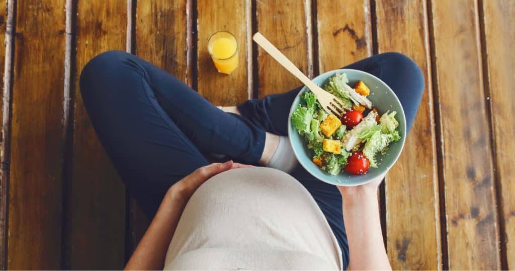 What can expectant parents do? A pregnant woman eating a salad https://www.autismparentingmagazine.com/can-autism-be-detected-before-birth/